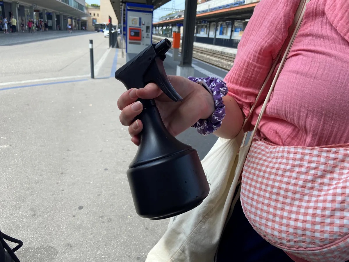 Eine Frau hält eine Wasser-Spritzpistole für Pflanzen in der Hand.